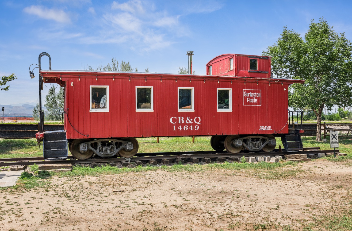 The red CB&Q 14649 caboose on a short length of track at Whistle Stop Park, strung with festoon lighting